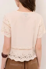 Camisa azul de manga corta confeccionada en tejido broderie con diseño calado y floral. Cuenta con escote en V y cierre frontal de botones.