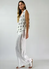 Pantalón blanco de lino con paneles de red en los laterales.