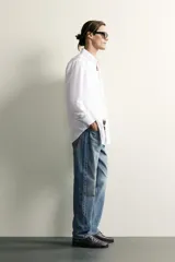 Jeans regular fit de mezclilla negra con efecto lavado, corte recto y tiro medio. Cuenta con diseño de cinco bolsillos y cierre frontal con cremallera y botón.