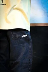 Jean baggy gris con efecto gastado, tiro alto, corte ancho de piernas y costuras decorativas diagonales en el frente.