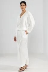 Pantalón blanco de lino italiano, de pierna ancha, con cintura elástica ajustable con cordón, bolsillos laterales y cortes redondeados en los laterales.