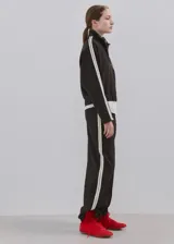 Pantalón deportivo negro con líneas blancas laterales, tiro alto y diseño recto.