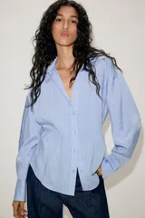 Camisa de manga larga con cuello solapa y escote en pico. Presenta un diseño entallado en la cintura y cierre frontal mediante botones.