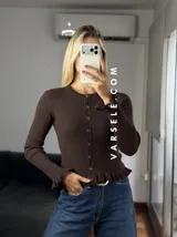 Saquito de tejido bremer color crema, con cuello redondo, cierre frontal de botones y detalles de volados en el ruedo y los puños.