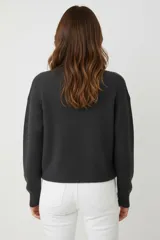 Sweater de tejido liso, color marrón oscuro, con cuello redondo a la base y calce holgado.