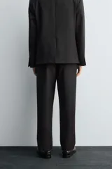 Pantalón de traje corte straight fit confeccionado en tejido mezcla de lana. Presenta cierre frontal con cremallera y botón, bolsillos laterales y bolsillos traseros de vivo.