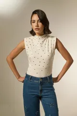 Body sin mangas de algodón, con cuello alto y diseño ajustado al cuerpo, decorado con tachas metálicas distribuidas por toda la prenda.