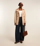 Trench coat de corte sastrero color beige, con cuello solapa, cierre frontal de doble botonadura y acabado satinado.