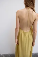 Vestido midi color amarillo con cuello halter, espalda descubierta y lazada en el mismo tejido.