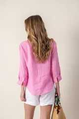 Camisa color coral de lino con cuello clásico, manga 3/4 y cierre frontal con botones.