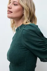 Blusa de color gris oscuro con diseño de punto smock en el cuerpo, cuello redondo y mangas cortas abullonadas con detalle de volados en el ruedo.