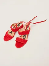 Sandalias de gamuza color rojo, con taco ancho de charol y tiras cruzadas con detalles trenzados. Cuentan con una correa fina ajustable al tobillo.