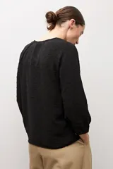 Blusa negra de manga larga con diseño de tejido plumeti y escote en V.