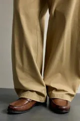 Mocasín de vestir de cuero color marrón, con diseño tipo antifaz en el empeine, costuras visibles en la puntera y suela a contraste.