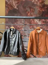 Campera bomber color marrón de cuero sintético con cierre frontal, cuello clásico y puños elásticos.