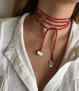 Gargantilla roja de múltiples vueltas con cuentas plateadas y dijes redondos.