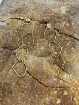 Par de caravanas colgantes doradas con forma de rombos unidos entre sí.