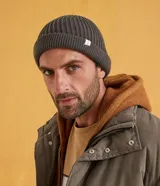 Gorro tipo fisherman de tejido acrílico con textura acanalada, diseño corto y etiqueta pequeña con logo en el frente.