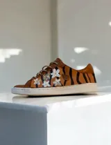 Championes de cuero terracota con diseño pintado a mano de rayas de tigre y flores blancas, suela de goma blanca y cordones al tono.