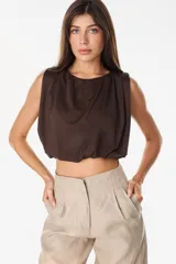 Top cropped satinado de color blanco, sin mangas, con hombros marcados y drapeado frontal.