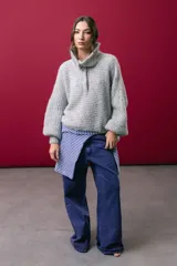Buzo tejido en mohair de color gris, con silueta amplia y corte en línea A. Presenta cuello tipo remera con broches que permiten cerrarlo como polera, mangas largas con puños y un diseño de tejido horizontal.