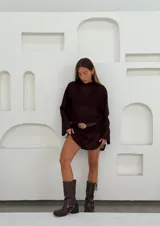 Remerón tipo vestido marrón de tejido de red con mangas largas y cinturón de cuero marrón con hebilla dorada.