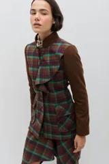 Chaqueta de lana en tono verde oliva con textura jaspeada, cuello mao y detalle de volado frontal. Presenta un corte entallado, bolsillos delanteros con solapa y cierre frontal con botones.