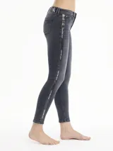 Jeans de mezclilla gris oscuro lavado, corte skinny y talle medio, con una banda lateral vertical que lleva el texto "Calvin Klein Jeans" repetido.