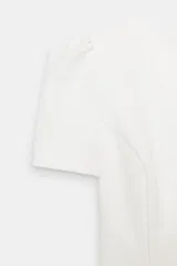 Vestido corto de Zara, color blanco, con escote en pico, mangas cortas abullonadas y detalle de lazo frontal en el mismo tejido. Presenta un corte entallado y cierre de cremallera oculta en la espalda.