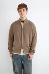 Chaqueta de punto de algodón color marrón, con cuello alto y cierre frontal con cremallera.