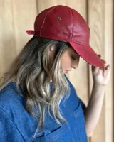 Gorra tipo visera confeccionada en cuero con textura de pelo, diseño clásico con ojales metálicos de ventilación y ajuste posterior.