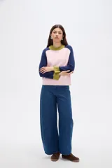 Sweater de punto con diseño color block, presenta cuerpo en color rosado, mangas en azul marino y detalles de cuello y puños en color verde oliva. Posee un corte holgado y cuello redondo a la base.