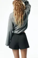 Short pollera de sarga color negro, con diseño cruzado en el frente de corte asimétrico que simula una falda por delante y short por detrás.