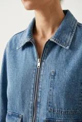 Campera de denim azul oscuro, de corte clásico y calce recto, con cierre frontal metálico completo, cuello camisero, mangas largas y bolsillos frontales aplicados con solapa.