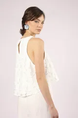 Blusa blanca de broderie con cuello redondo y sin mangas.