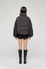 Campera tipo bomber acolchada, color negro, con cuello alto, cierre frontal con cremallera y diseño de mangas amplias.