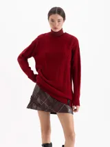 Sweater de punto color rojo con diseño de trenzas verticales y textura estructurada. Presenta cuello redondo, mangas largas y un corte holgado con terminaciones acanaladas.