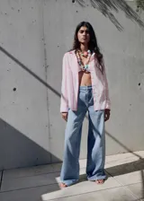 Camisa de corte recto y diseño holgado, con estampado de rayas verticales en tonos blanco y rosado. Presenta cuello camisero clásico, cierre frontal con botones ocultos y mangas largas.