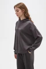 Canguro con capucha de calce holgado, color bordó, con detalle de aplique de strass en el pecho.