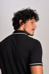 Polo de manga corta confeccionado en tejido interlock suave, color negro con detalles de vivos en color blanco en el cuello y las mangas. Presenta tapeta con botones y un bolsillo frontal con el logo bordado.