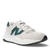 Championes urbanos New Balance modelo 57/40, color beige con detalles en verde y blanco, confeccionados en gamuza y malla, con logo "N" característico en los laterales y entresuela blanca.