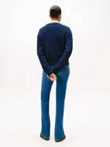 Sweater de punto con diseño de trenzas, cuello redondo y detalle de botones dorados en el hombro. Presenta terminaciones acanaladas en puños y dobladillo, con logo bordado en el pecho.