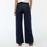 Pantalón de jean azul oscuro con corte wide leg, cintura alta y cierre frontal con botones a la vista. Presenta bolsillos frontales tipo parche.