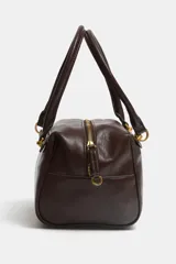 Bolso de hombro tipo bowling o mini shopper, color marrón oscuro, con doble asa superior y herrajes metálicos dorados. Presenta un diseño estructurado y compacto.