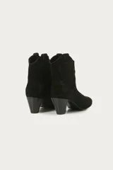 Bota corta estilo texano con taco medio de 6 cm. Confeccionada en cuero gamuzado, presenta recortes laterales que emulan la forma de una mariposa. Diseño de punta fina y caña media.