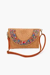 Bandolera de fibra natural tejida en color marrón, con solapa decorada con canutillos y cuentas multicolores en forma de semicírculo. Incluye correa larga ajustable de cuero sintético marrón y herrajes metálicos.