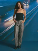 Pantalón de corte recto y tiro medio, confeccionado en material con acabado encerado color gris oscuro. Presenta costuras decorativas verticales a lo largo de las piernas y costura horizontal a la altura de la rodilla, con bolsillos laterales y cierre frontal.