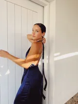 Vestido largo de seda lavada color verde esmeralda, con escote cruzado, falda en capas y flecos negros en el ruedo.