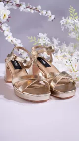 Sandalias de tacón bajo color dorado, con tiras cruzadas en el empeine, pulsera al tobillo con hebilla y plantilla acolchada.