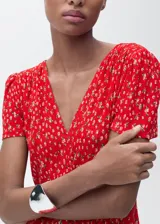 Vestido midi de corte recto con estampado floral, cuello en pico y mangas cortas. Presenta una abertura lateral en la falda y cierre de cremallera lateral.